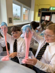Children engaging in fun science experiment with colorful slime in classroom.