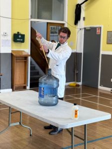 Young man pouring water into a container during a community event or workshop.