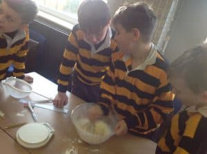 Students cooking class at Inchmarlo with kids in school uniforms.