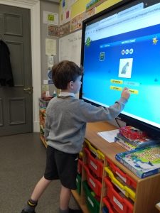 Young boy using interactive touchscreen in classroom, engaged in digital learning at Inchmarlo.