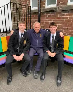 Image of two students and an adult sitting on a colorful bench at Inchmarlo School, showcasing a welcoming educational environment.