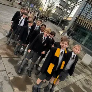 Children walking in school uniforms outside modern building, urban setting, day shot.