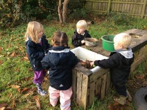 Group of young children engaging in outdoor soil play at Inchmarlo preschool.