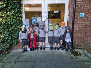 Group of children in costumes outside Inchmarlo school building.