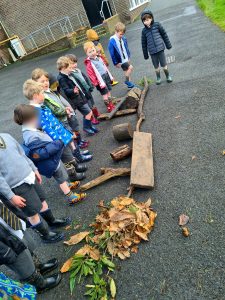 Children learning outdoors at Inchmarlo, interacting with natural elements and outdoor equipment.