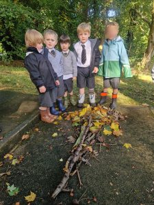 Group of children playing outdoors at Inchmarlo, surrounded by trees and fallen leaves.
