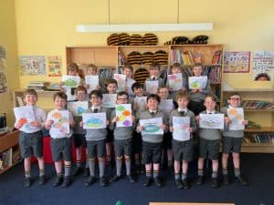 Group of children holding artwork in classroom at Inchmarlo school, promoting early education and learning environments.