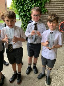 Three young boys in school uniform holding books outside Inchmarlo School, promoting education and student life.