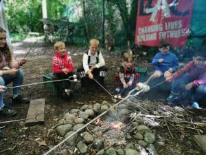 Children enjoying outdoor campfire activities at Inchmarlo estate.