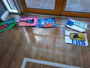 Colorful children's painted rocks artwork on wooden floor.
