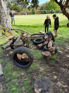 Children playing on outdoor tire and log play structures at Inchmarlo.