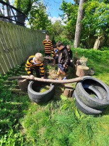 Children playing outdoor at Inchmarlo with tires and wooden logs.