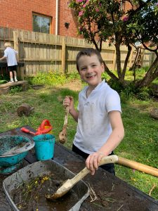 Happy boy gardening at Inchmarlo outdoor play area, children enjoying nature and recreational activities.
