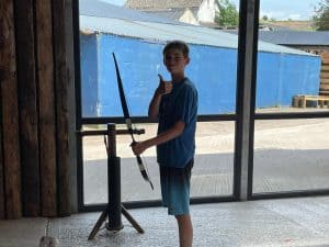 Young boy standing by a sculpture in an indoor space with large windows and blue exterior view.