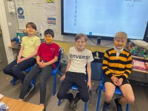 Students sitting in classroom along with a whiteboard in the background, highlighting educational environment and student engagement.