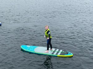 Person paddleboarding on a lake with scenic views.