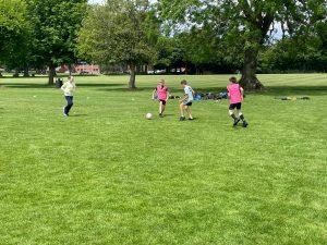 Children playing football in Inchmarlo Park, a scenic outdoor space in Scotland.