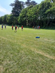 Children playing soccer on lush green field at Inchmarlo estate, surrounded by trees.
