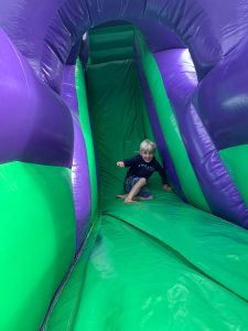 Child playing on inflatable slide at Inchmarlo outdoor activity park.