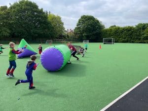 Children playing on outdoor sports field with large inflatable equipment, sunny day.