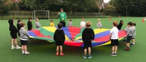 Children playing with colorful parachute in the outdoor setting of Inchmarlo.