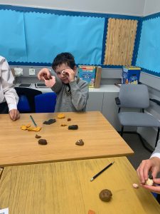 Boy smiling at table with clay toys in classroom, learning and playing.