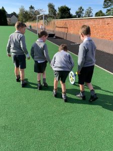 Children playing football on school sports field.