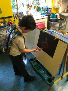 Young boy painting at Inchmarlo preschool classroom.