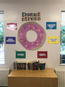 Colorful donut sign on wall, surrounded by various motivational quotes, with a bookshelf underneath.