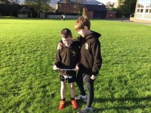 Two children studying outdoors at Inchmarlo, engaging in learning activities on a sunny day.