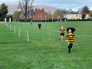 Children running on green sports field at Inchmarlo, outdoor activity, summer day, Scotland.