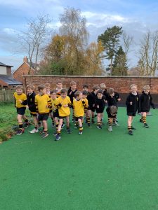 Young boys playing soccer outdoors on a green field, dressed in yellow and black uniforms.