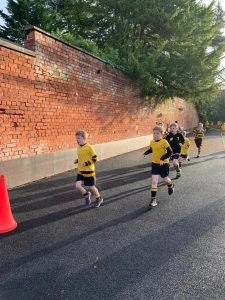 Children running during a charity event at Inchmarlo with a brick wall and greenery in the background.
