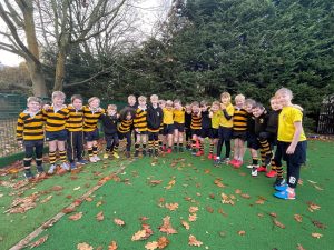 Children playing outdoor rugby game on grassy field at Inchmarlo school.