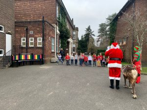 Festive event outside Inchmarlo with people, Santa, and a dog, celebrating community and holiday cheer.