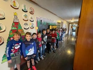 Children lining up in a school hallway at Inchmarlo during a festive event.