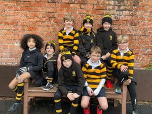 Group of school children wearing uniform outside brick wall.