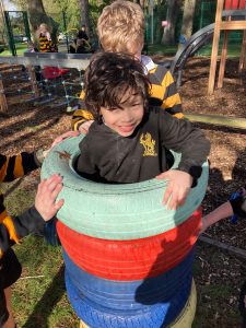 Children playing in colorful tire stack at Inchmarlo outdoor playground.