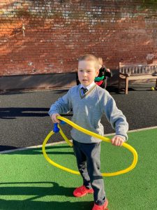 Child playing with a yellow hula hoop at Inchmarlo outdoor play area.