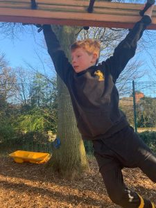 Child climbing on outdoor playground at Inchmarlo Estate, enjoying nature and outdoor activities.