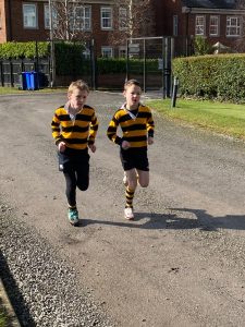 Two children running outdoors at Inchmarlo School, enjoying outdoor activities and fresh air.