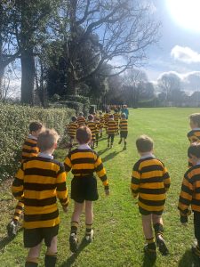 Children in striped rugby shirts playing outdoors at Inchmarlo School, enjoying open green space.