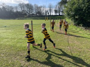 Girls playing rugby in sunny outdoor field at Inchmarlo.