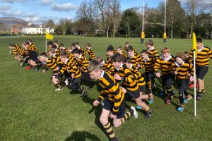 Children in yellow and black striped sports uniforms participate in a race on the athletic field.