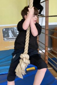 Child gripping a climbing rope at Inchmarlo therapy center.