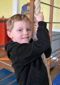 Young boy smiling and holding a climbing rope at Inchmarlo School.