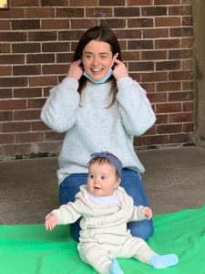 Smiling woman with a baby outdoors at Inchmarlo, enjoying a sunny day in a scenic park setting.