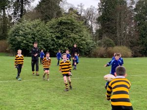 Children playing rugby outdoors at Inchmarlo in Scotland, surrounded by greenery.