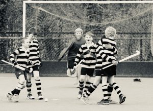 Group of children playing hockey on an outdoor field.