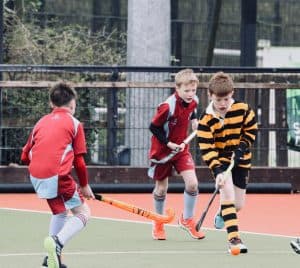 Children playing hockey on an outdoor field at Inchmarlo.